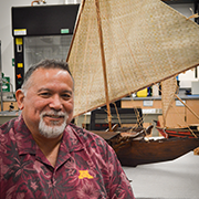 Vincente Diaz smiling next to a model of a boat